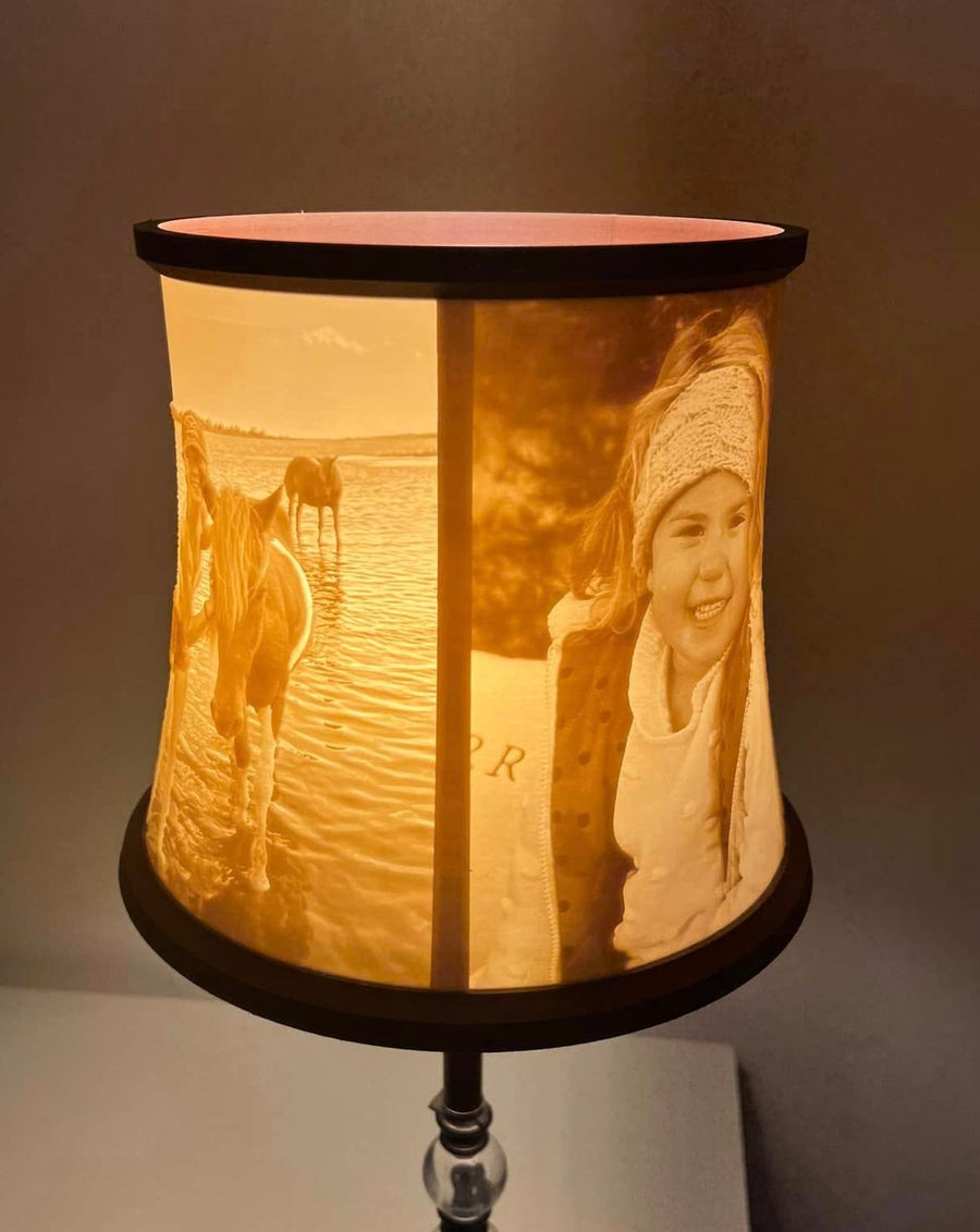 Bell-style lithophane lamp shade lit on a lamp, showing a child and horse photos